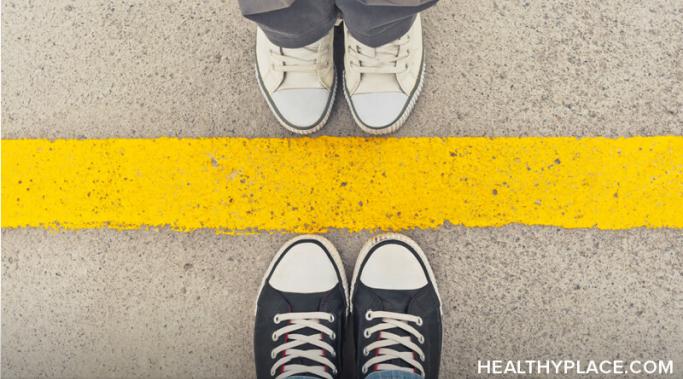 Stock image of two people's shoes facing each other separated by yellow lines. 